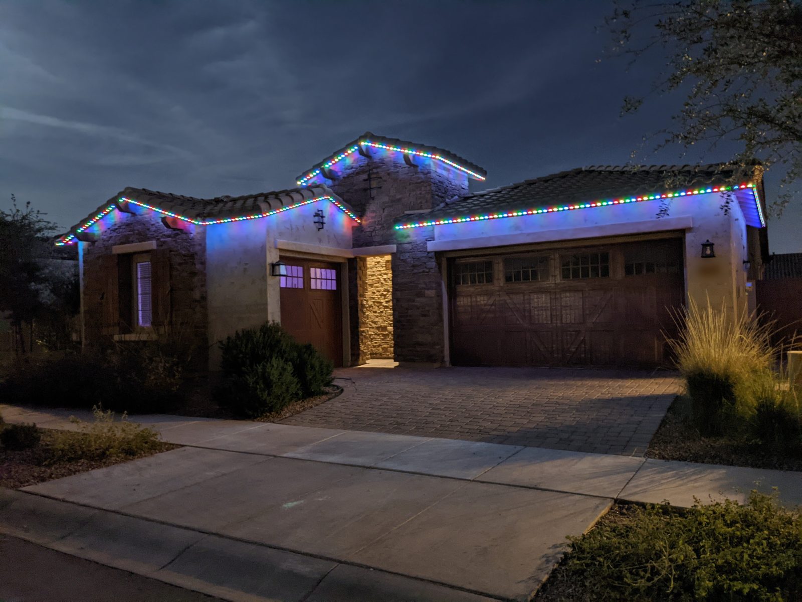 A single-story house at night with color-changing permanent lights along every roofline