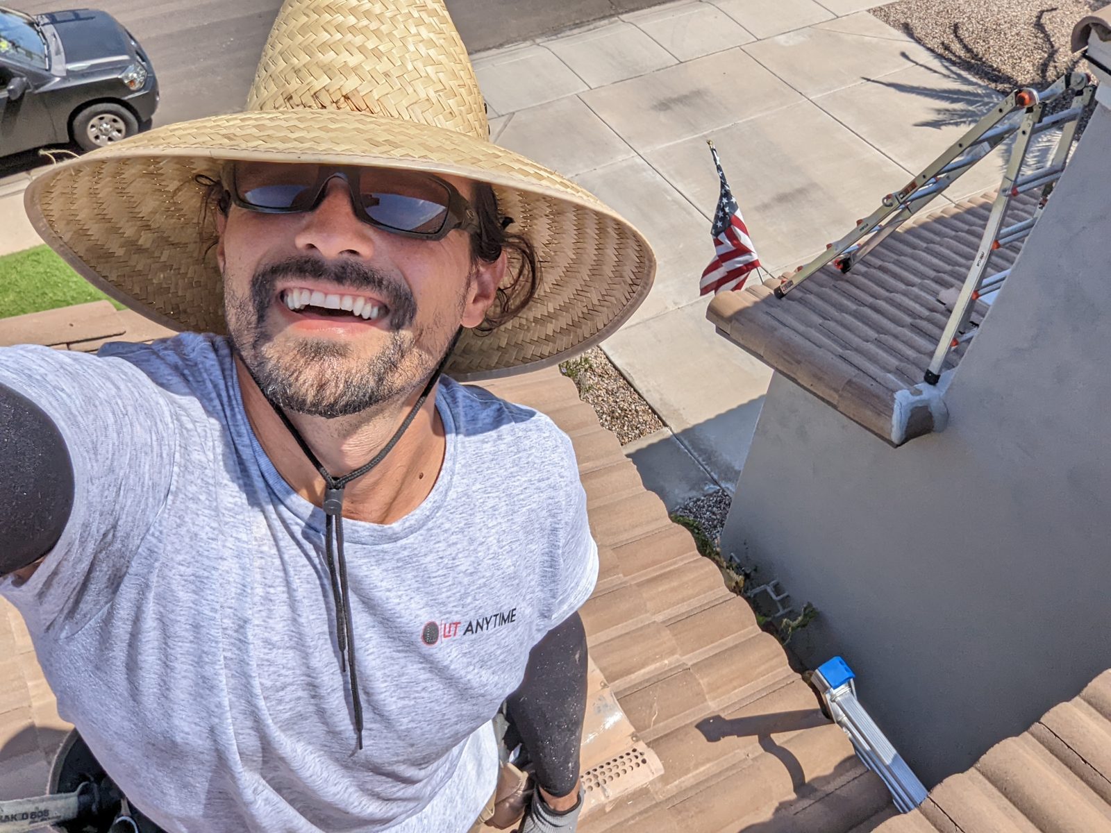 Steven in a straw hat and Lit Anytime shirt on a tile roof during an install